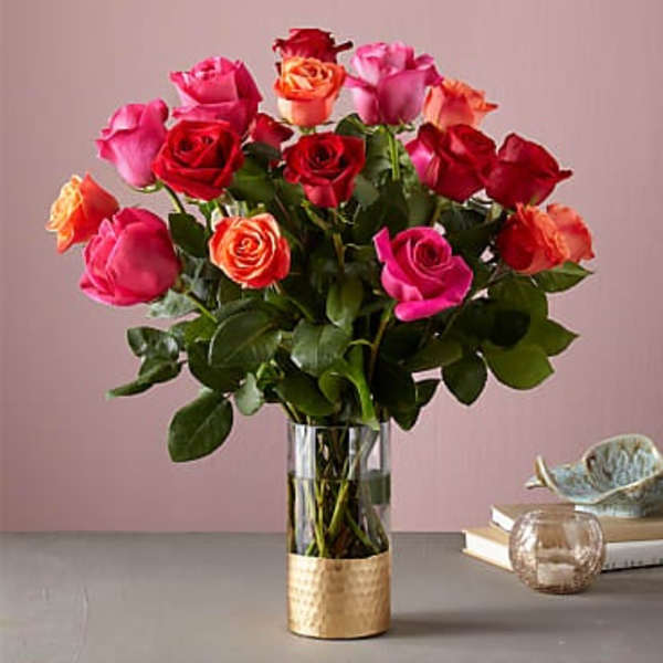 Bouquet of red, pink, and orange roses in a glass vase