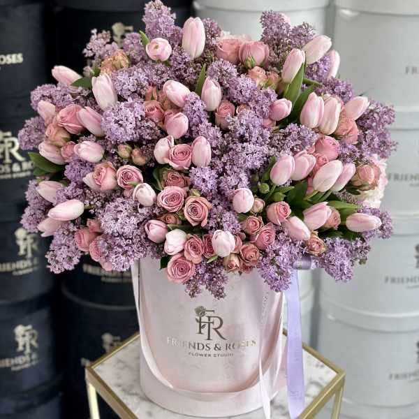 Pink roses and tulips arranged in a pale pink hatbox