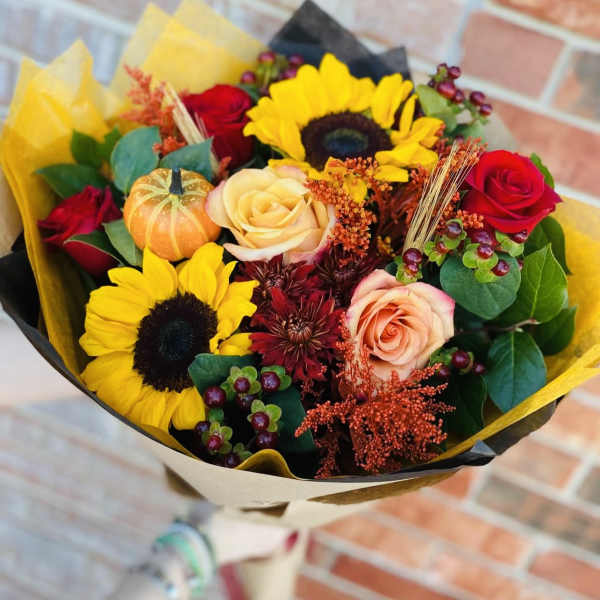 Bouquet of sunflowers and roses wrapped in yellow and black paper