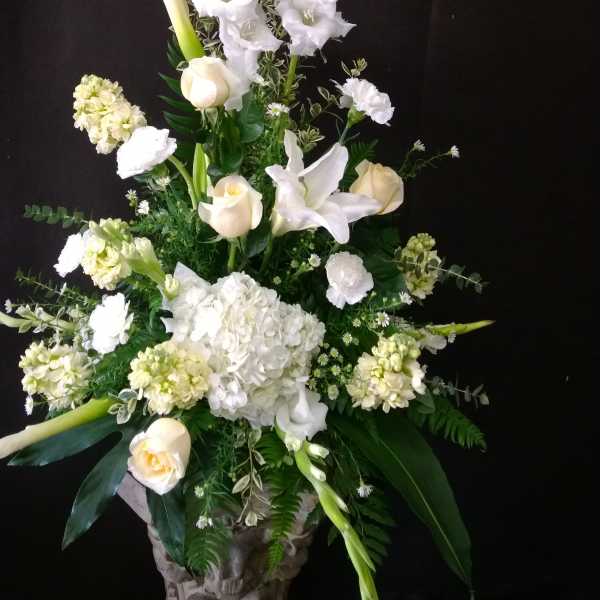 Tall white floral arrangement in a carved stone vase