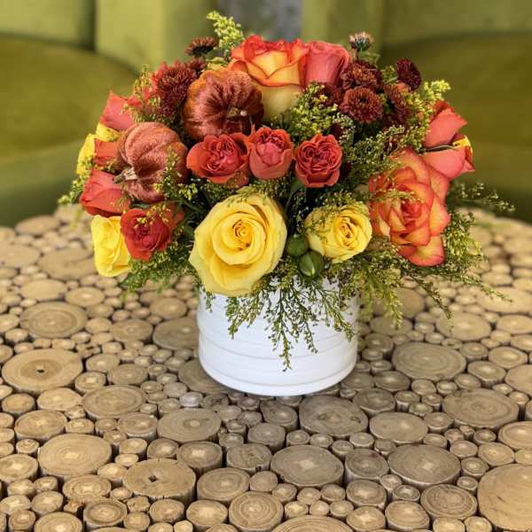 Bouquet of yellow and orange roses in a white container
