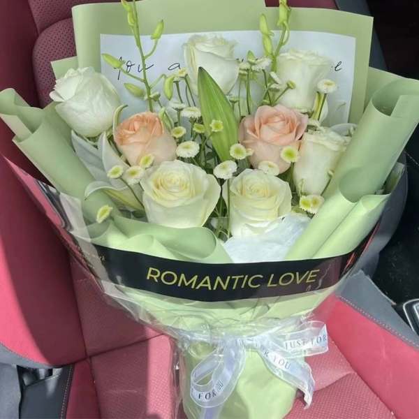 Bouquet of white and blush roses wrapped in pale green paper