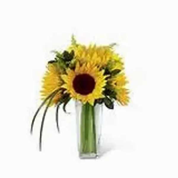Tall bouquet of yellow sunflowers in a clear glass vase with a few decorative grass blades
