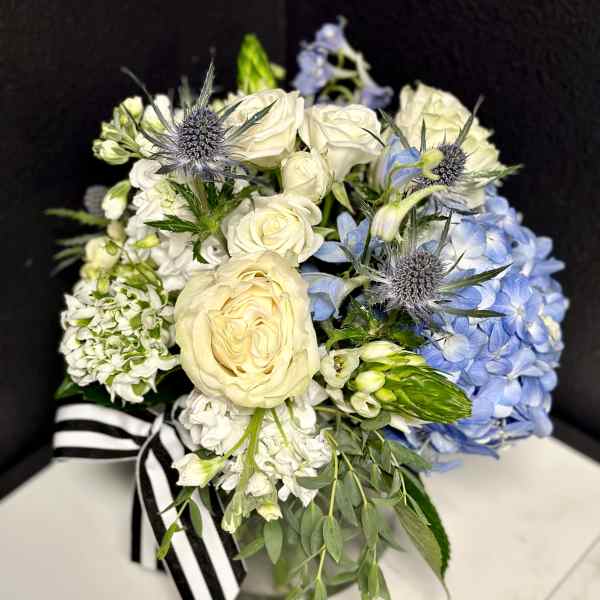 Bouquet of white roses and blue hydrangeas with thistle accents