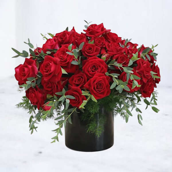 Low arrangement of red roses in a black cylinder vase