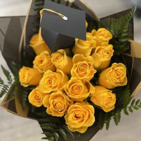Bouquet of yellow roses wrapped in dark paper with a black tag