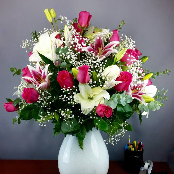 Pink roses and white lilies in a white vase