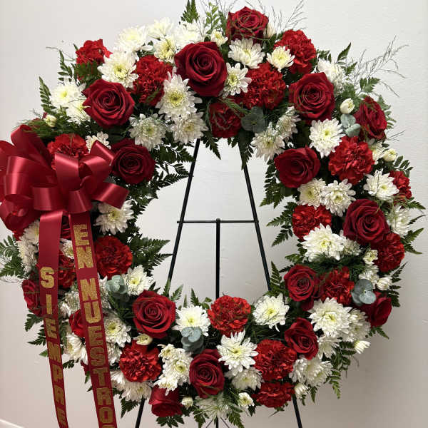 Heart-shaped wreath of red roses, white daisies, and red carnations on an easel