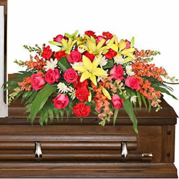Bright floral spray arranged on a wooden casket