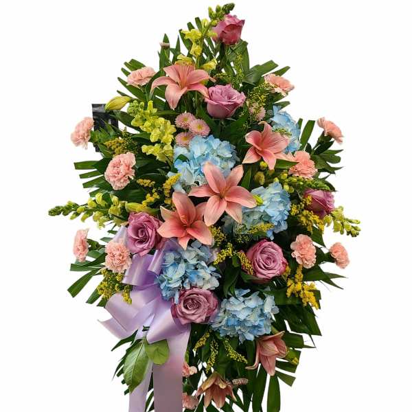 Standing floral spray with pink lilies, roses, and blue hydrangeas