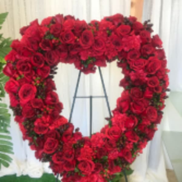 Heart-shaped red rose funeral wreath on a stand