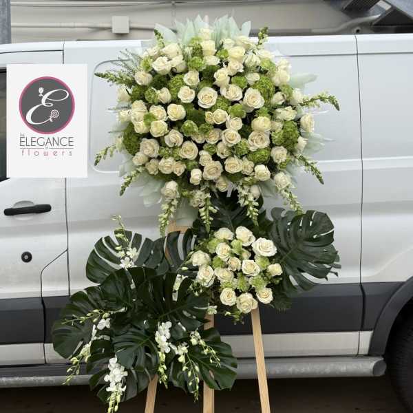 Large white rose and green floral standing arrangement on an easel