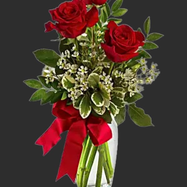 Red roses in a clear glass vase with a red ribbon