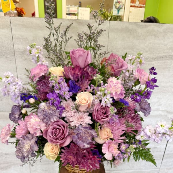 Large mixed bouquet of pink, purple, and cream flowers in a basket