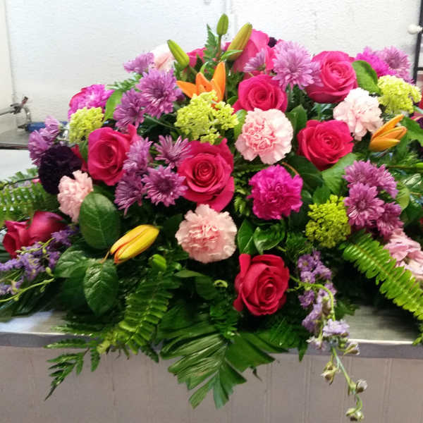 Large mixed floral arrangement with pink roses and purple blooms
