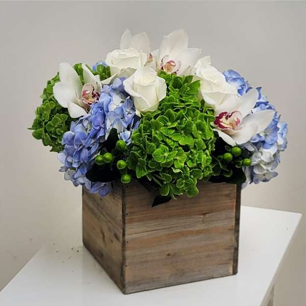 Blue hydrangeas and white roses in a wooden box