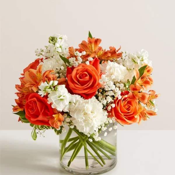 Orange and white flower arrangement in a clear glass vase