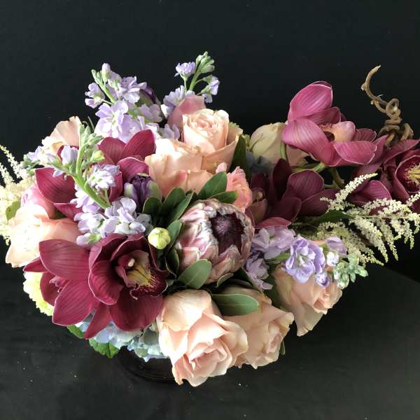 Bouquet of peach roses, burgundy orchids, and lavender flowers