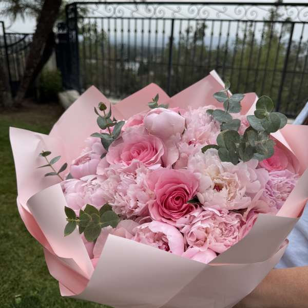 Pink bouquet of roses and peonies wrapped in pale pink paper