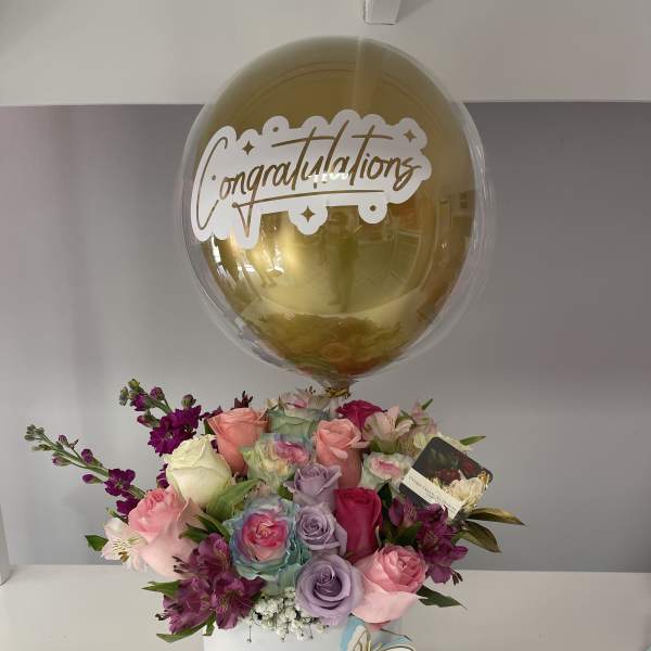 Bouquet of pastel roses in a white box with a gold congratulations balloon