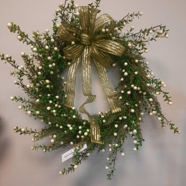 Green holiday wreath with white berries and a gold ribbon bow