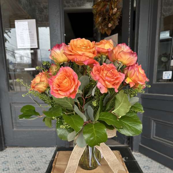 Bouquet of orange roses in a glass vase with a burlap ribbon
