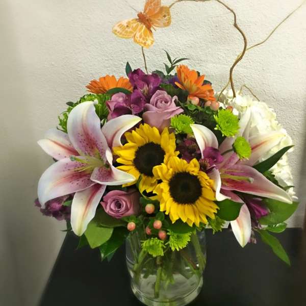 Mixed bouquet in a glass vase with sunflowers, lilies, and roses