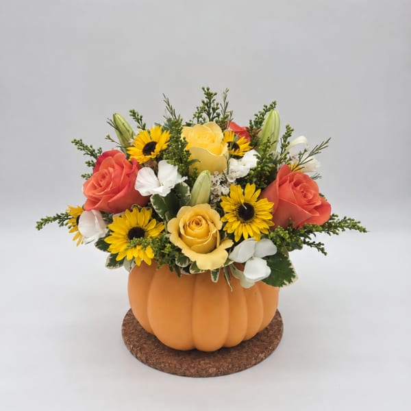 Flower arrangement in a pumpkin-shaped container with roses and sunflowers