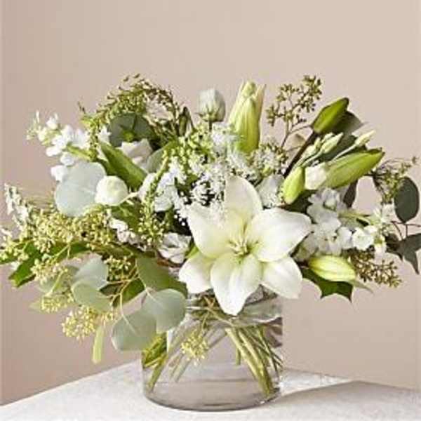 White lilies and green buds in a clear glass vase