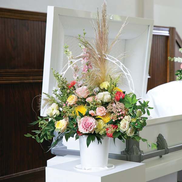 Floral casket spray with pink, yellow, and white flowers