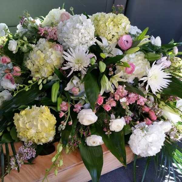 Large white and pink floral casket spray with lilies and hydrangeas