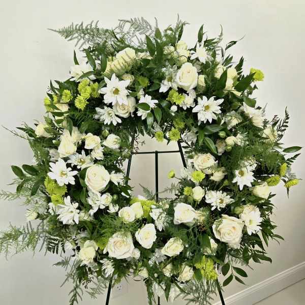 Large white and green floral wreath on a stand