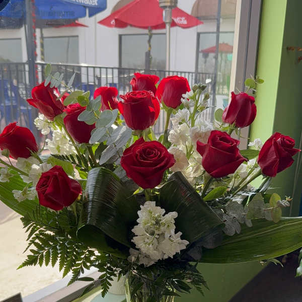 Red roses and white flowers arranged in a clear glass vase