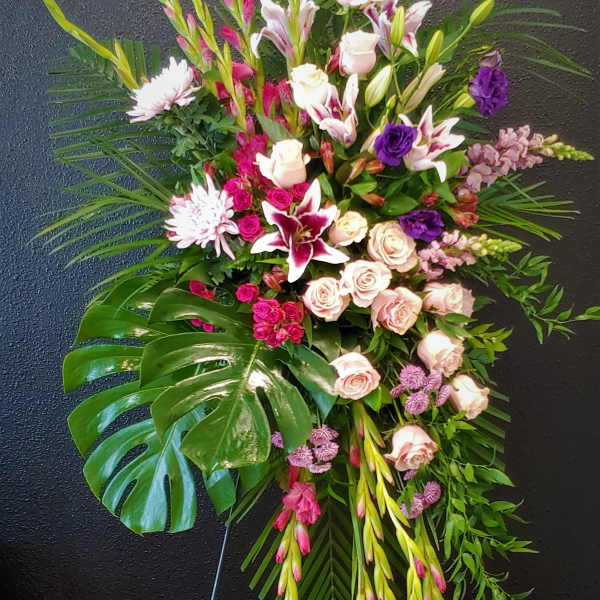 Standing floral spray with pink and white flowers on a black easel
