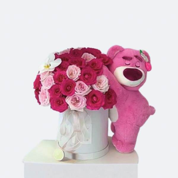 Pink rose bouquet in a silver box beside a pink teddy bear