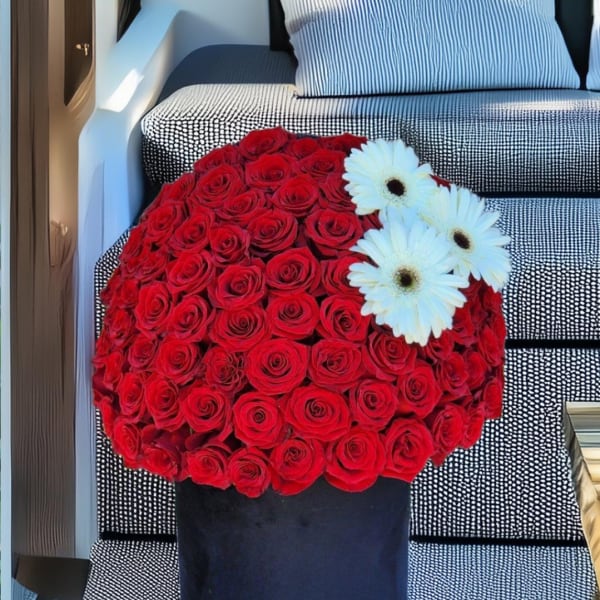 Round bouquet of red roses with white daisies in a black box