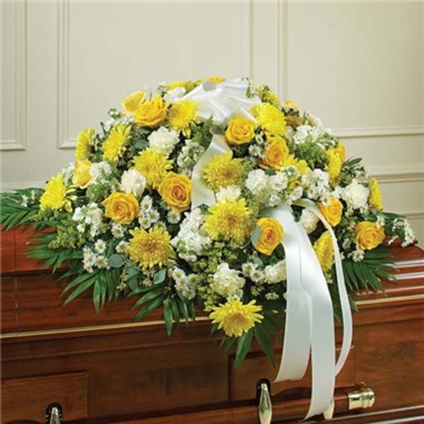 Yellow and white funeral spray on a casket with white ribbon