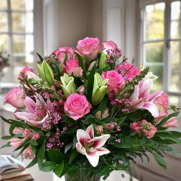 Pink roses and lilies arranged in a glass vase