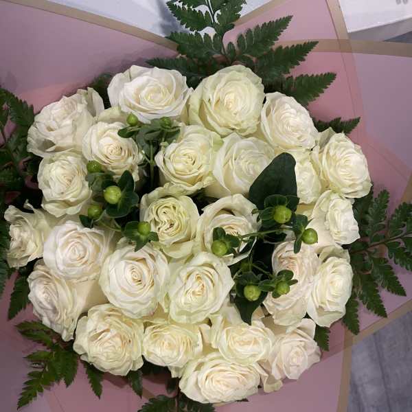 Bouquet of white roses wrapped in pink paper