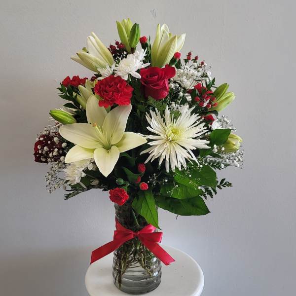 Bouquet of red and white flowers in a glass vase with a red ribbon