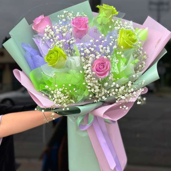 Bouquet of pink and green roses with baby's breath in pastel wrapping