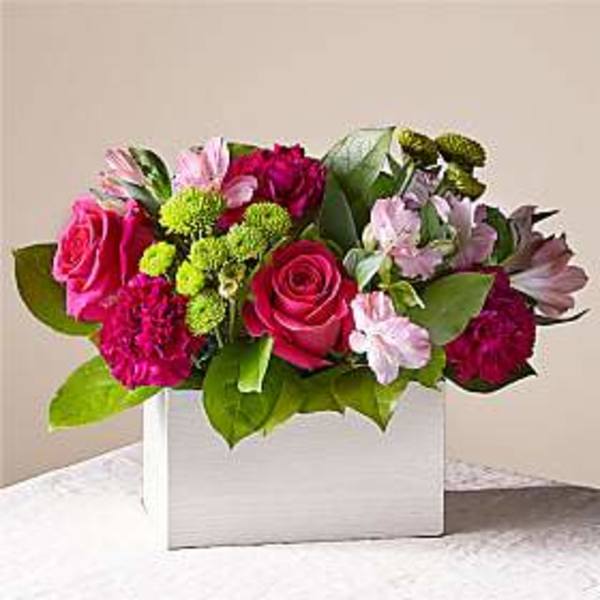 Pink and magenta flower arrangement in a white box