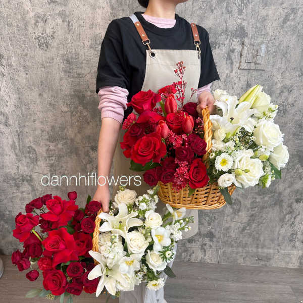Person holding large baskets of red and white flower arrangements