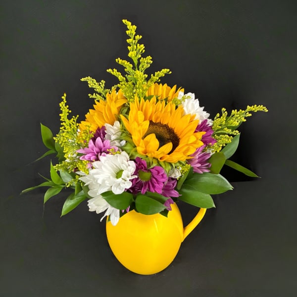 Sunflower and daisy bouquet in a yellow pitcher vase