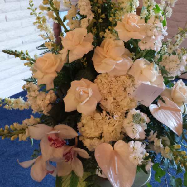Tall white floral arrangement with roses, orchids, and lilies