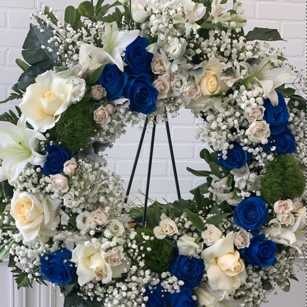 Heart-shaped floral wreath with blue and cream roses on a stand