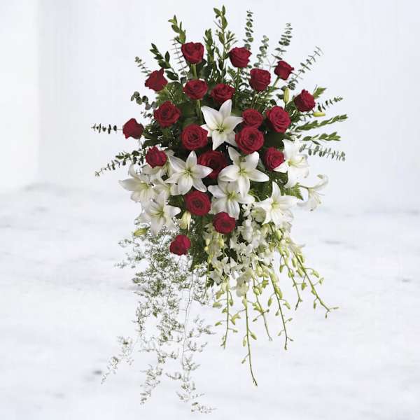 Standing arrangement of red roses and white lilies with trailing greenery