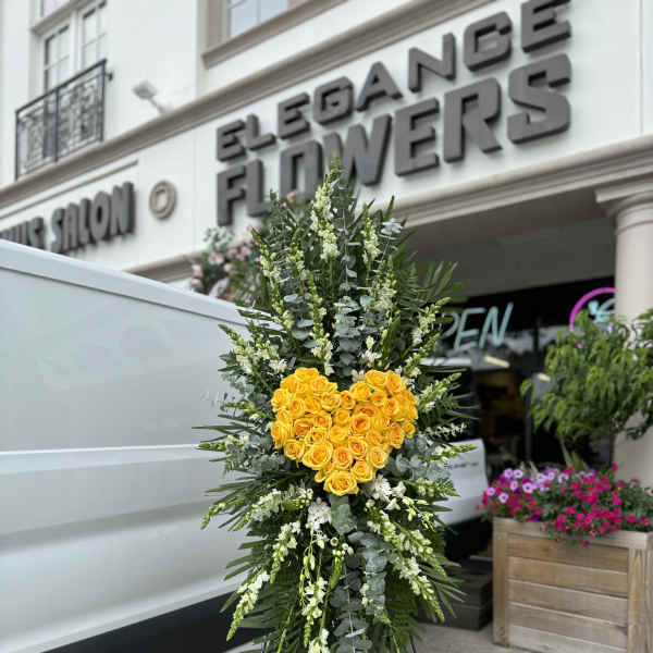 Standing floral tribute with yellow roses arranged in a heart shape