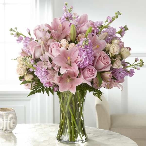 Pink lilies and roses arranged in a clear glass vase