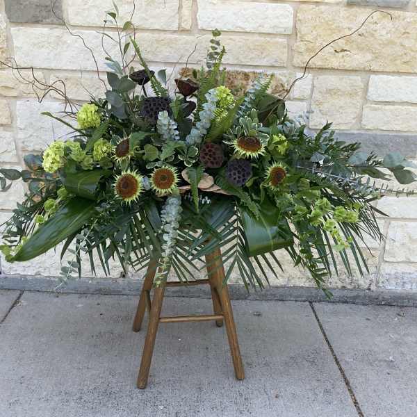 Large floral spray with sunflowers and greenery on a wooden stand